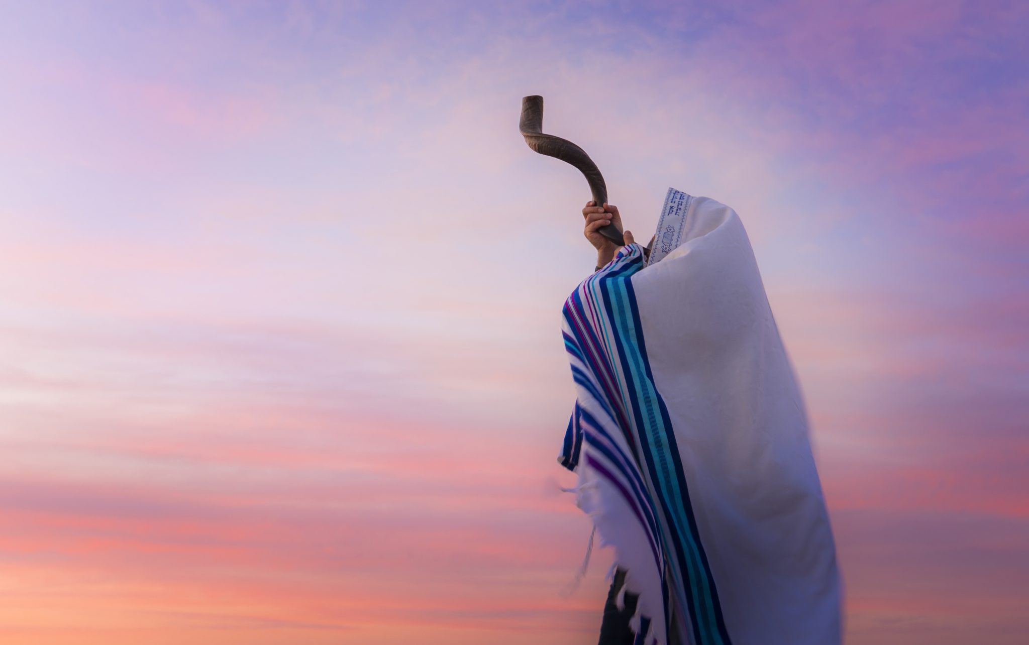 Blowing the Shofar man in a tallith, Jewish prayer shawl is blowing
