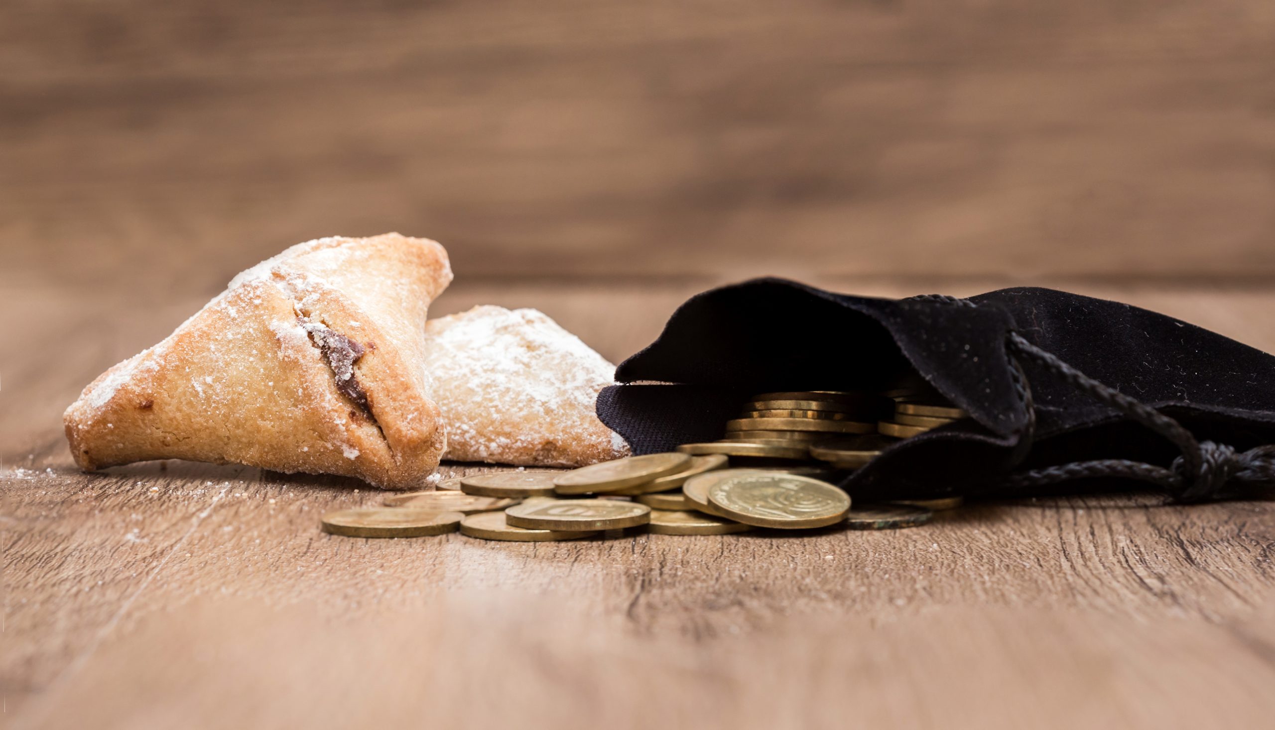 Purim holiday cookies, "Ozne Haman" in Hebrew. Haman's ears. With a bag of gold coins. Money for Purim | Foto: © Adobe Stock