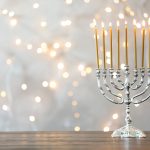 Hanukkah menorah with candles on table against blurred lights Foto: © Adobe Stock