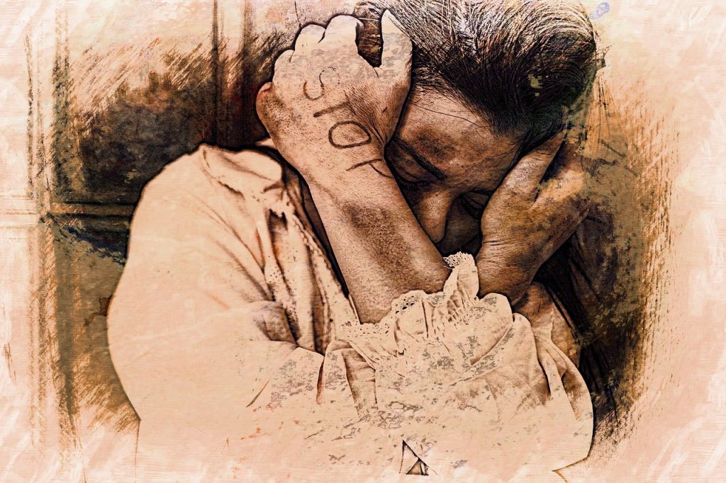 Eine Frau versteckt sich hinter ihren Armen. Auf dem Arm steht STOP